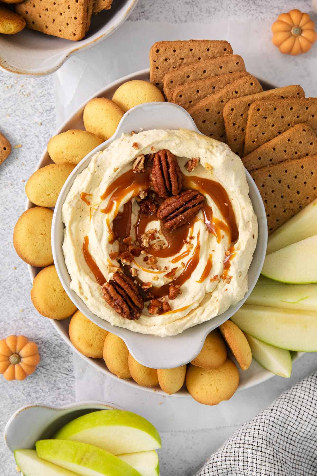 Pumpkin cheesecake dip served on a platter with cookies, graham crackers, and apple slices