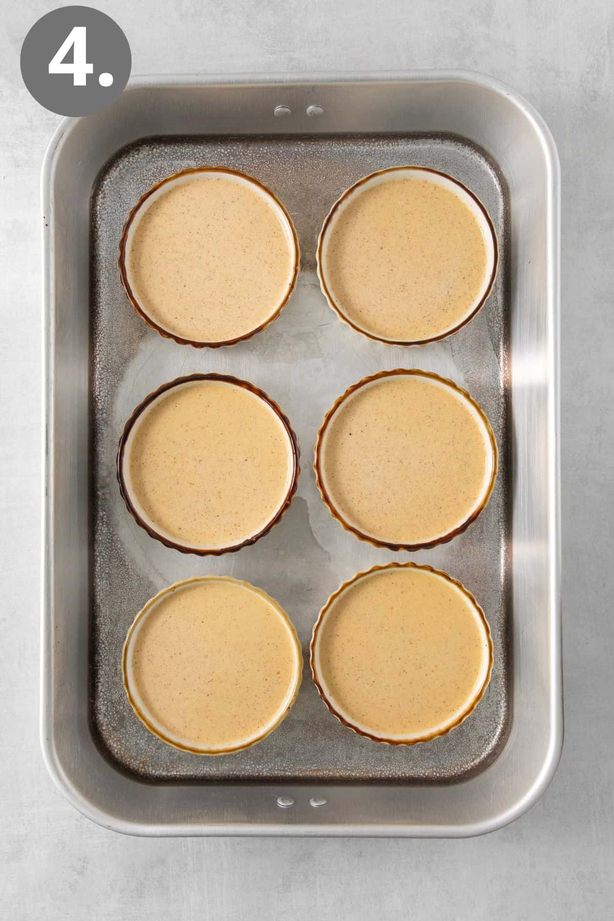 Uncooked pumpkin creme brulee in ramekins on a baking tray