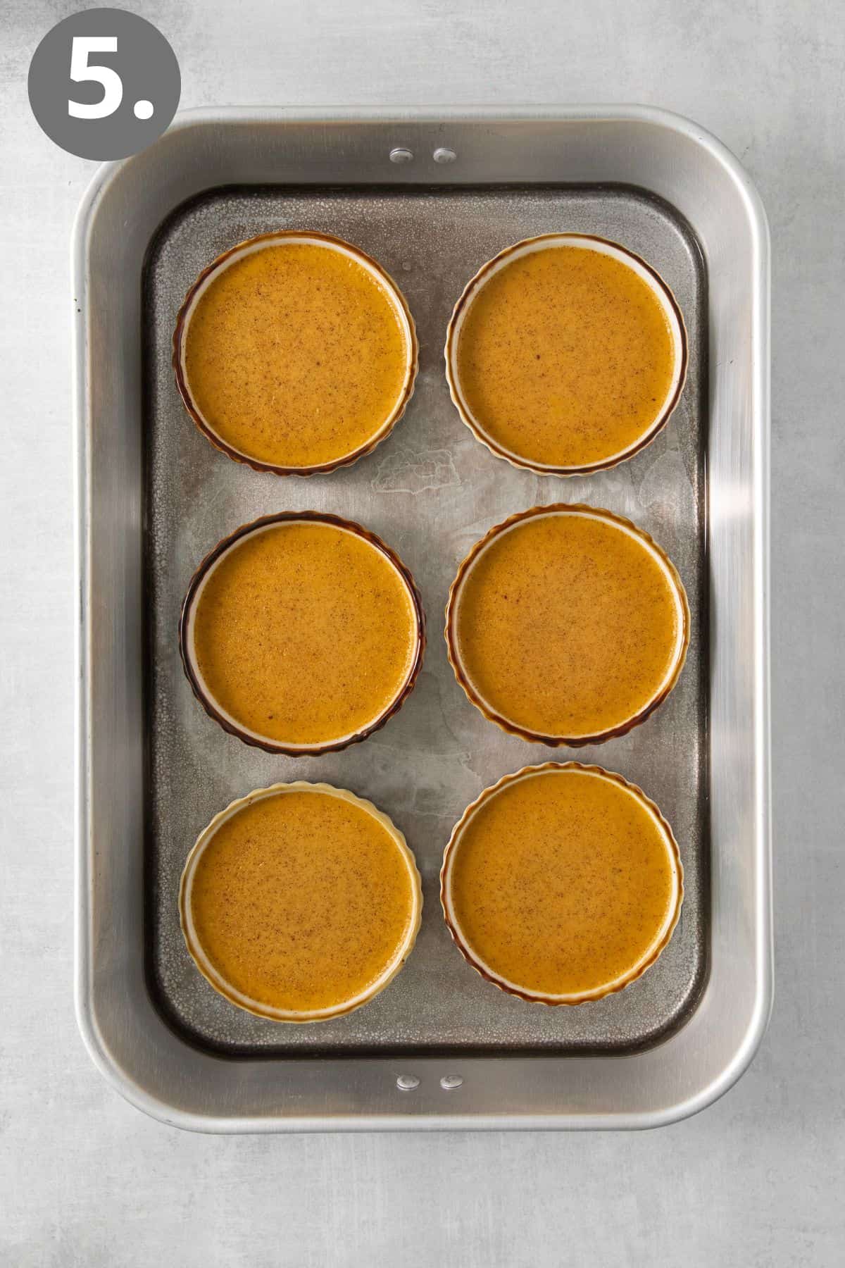 Baked pumpkin creme brulee in ramekins on a baking tray