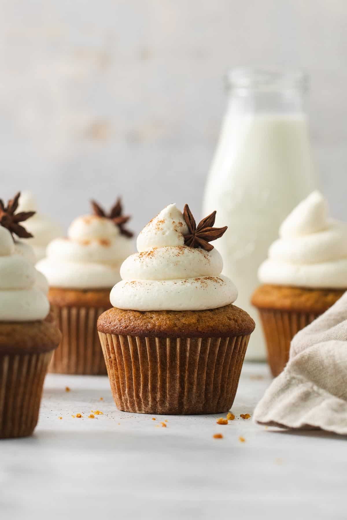 Gluten-free pumpkin cupcakes on a countertop with milk in the background