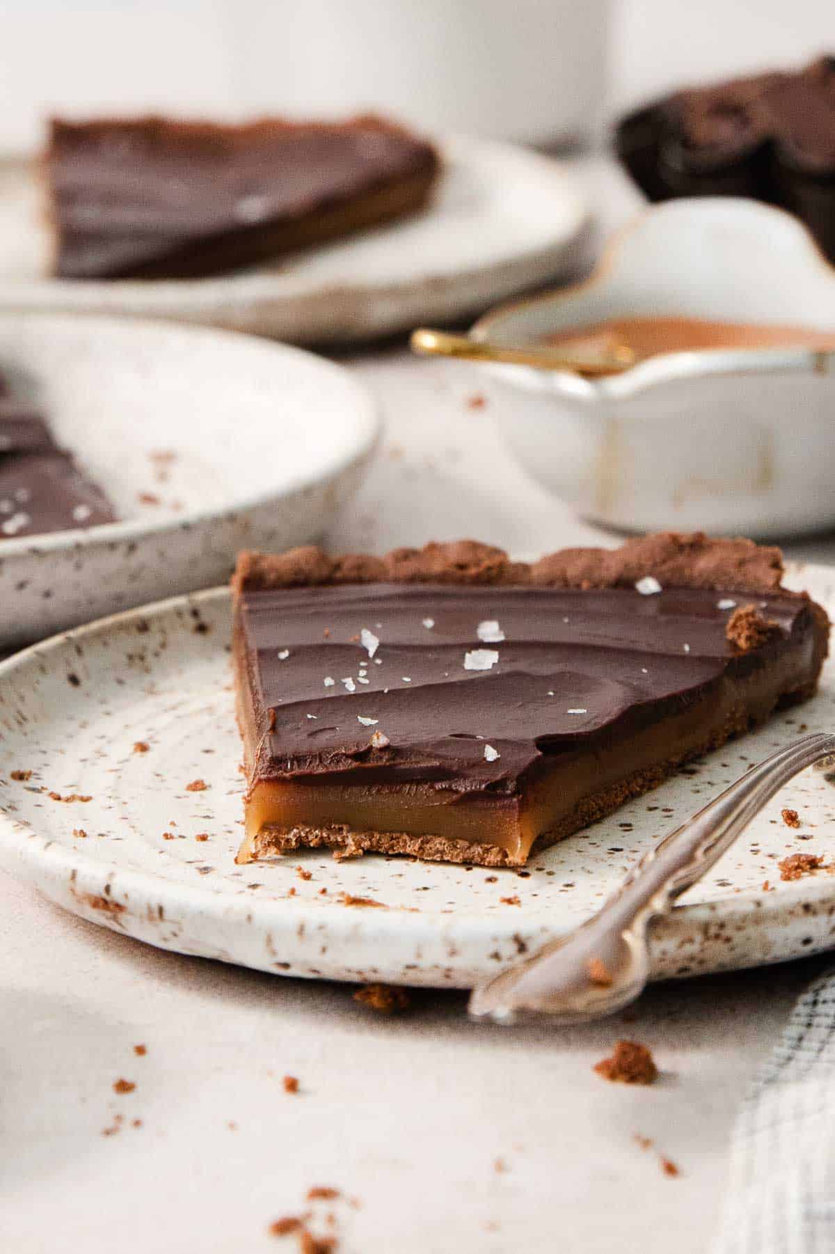 a slice of gluten-free chocolate caramel tart on a plate