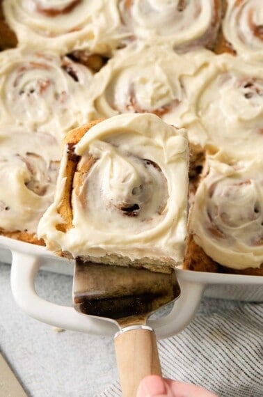 A serving spatula taking gluten-free cinnamon rolls out of the pan