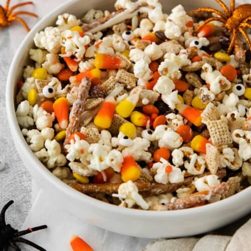 Halloween snack mix in a white bowl with spider decorations