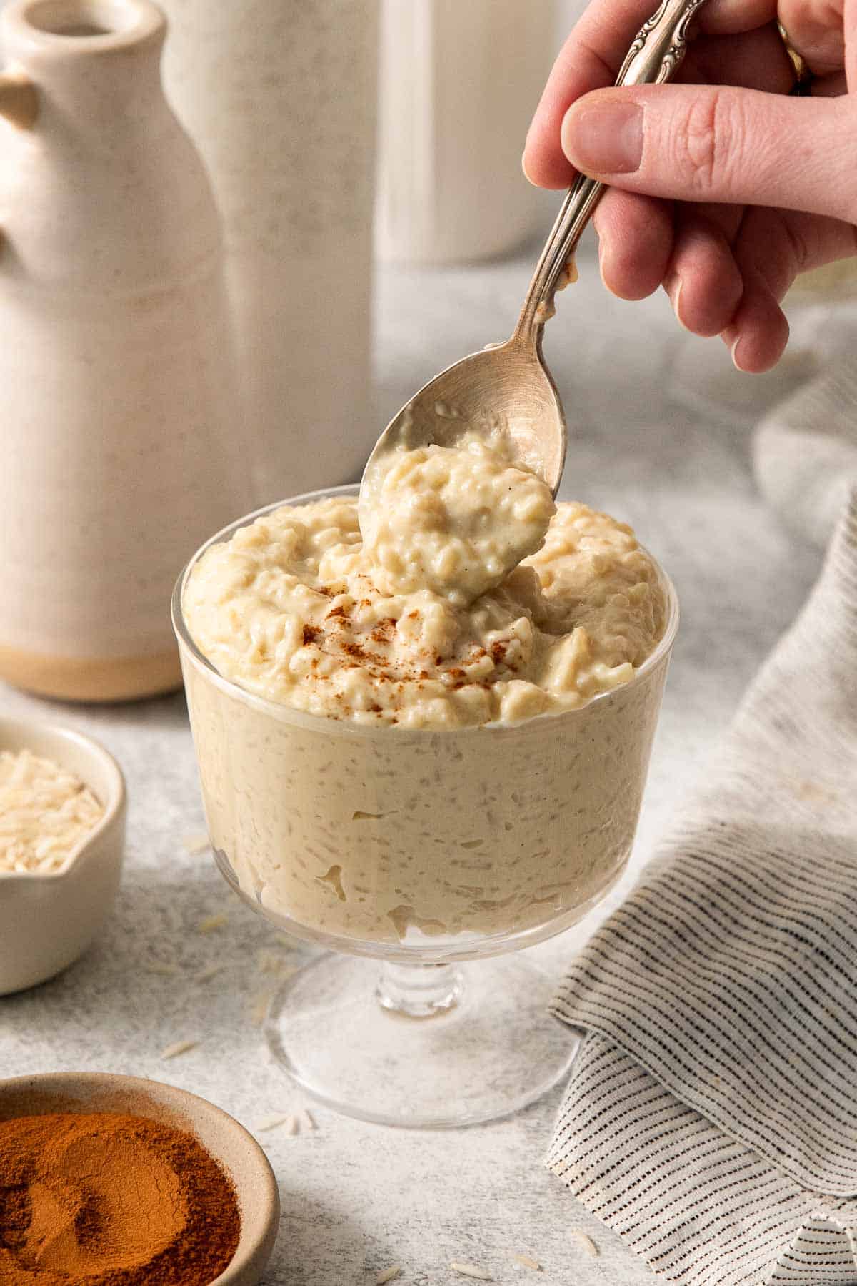 dairy-free rice pudding in a glass far, with a spoon dipping into the jar