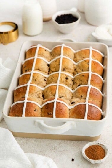 baked and iced hot cross buns in a baking pan