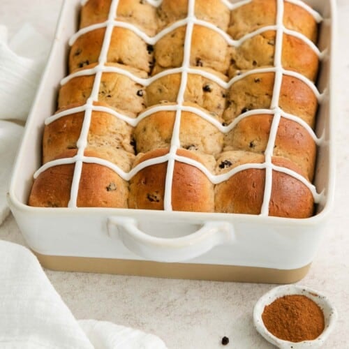 baked and iced hot cross buns in a baking pan