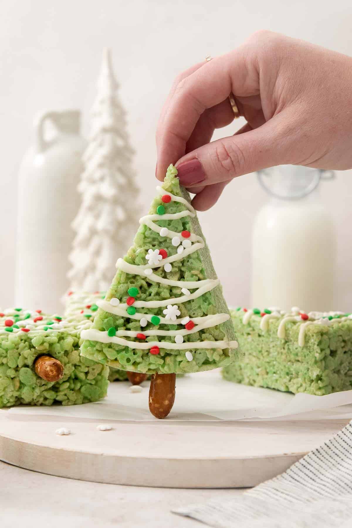a hand holding up one Christmas tree crispy treat with more behind.