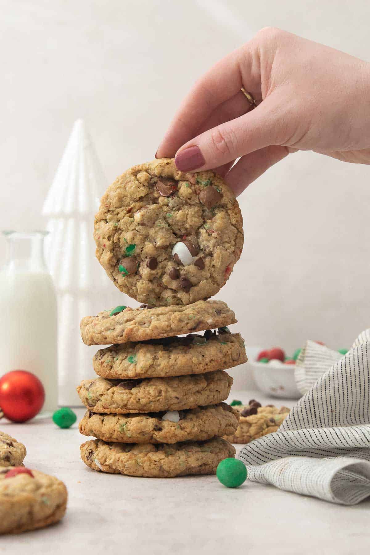 a hand holding up one cookie on top of a tower of Cadbury Snowball cookies.