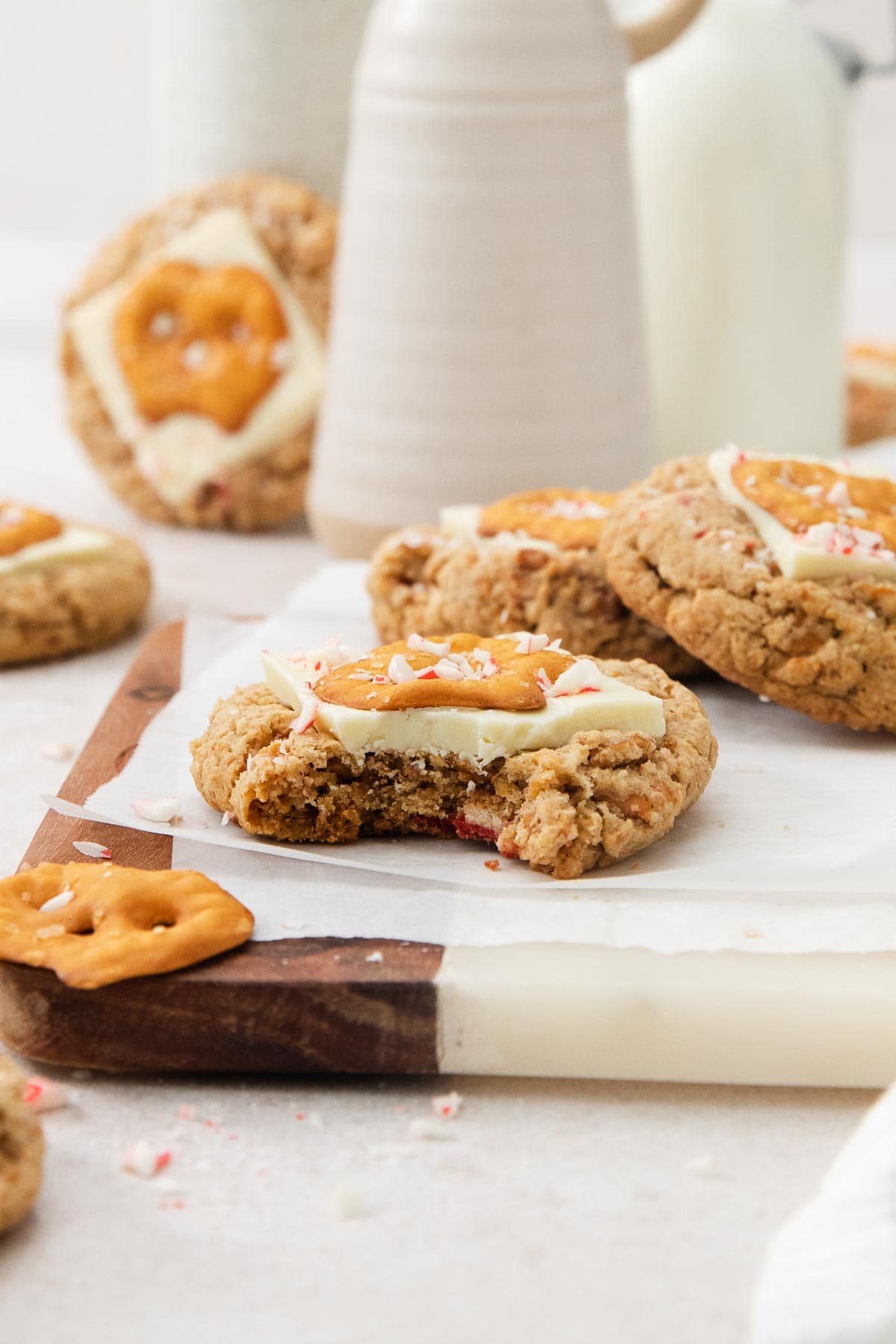 one white chocolate peppermint pretzel cookie with a bite missing with more behind.