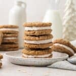 eggnog oatmeal cream pies stacked on a plate with more in the background.