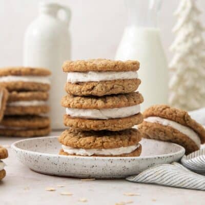 eggnog oatmeal cream pies stacked on a plate with more in the background.