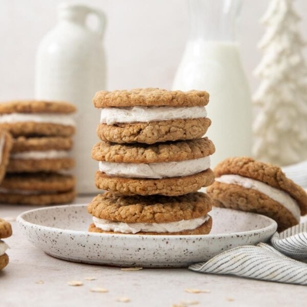 eggnog oatmeal cream pies stacked on a plate with more in the background.