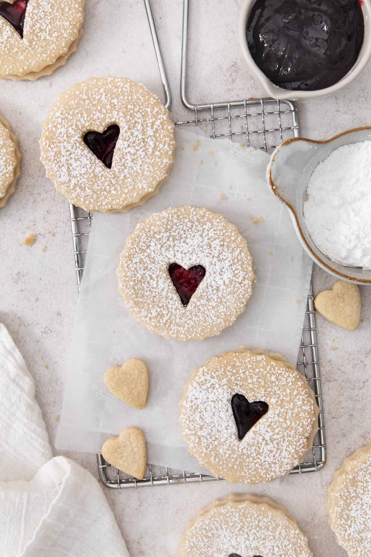 jam-filled linzer cookies on parchment paper and a wire rack.
