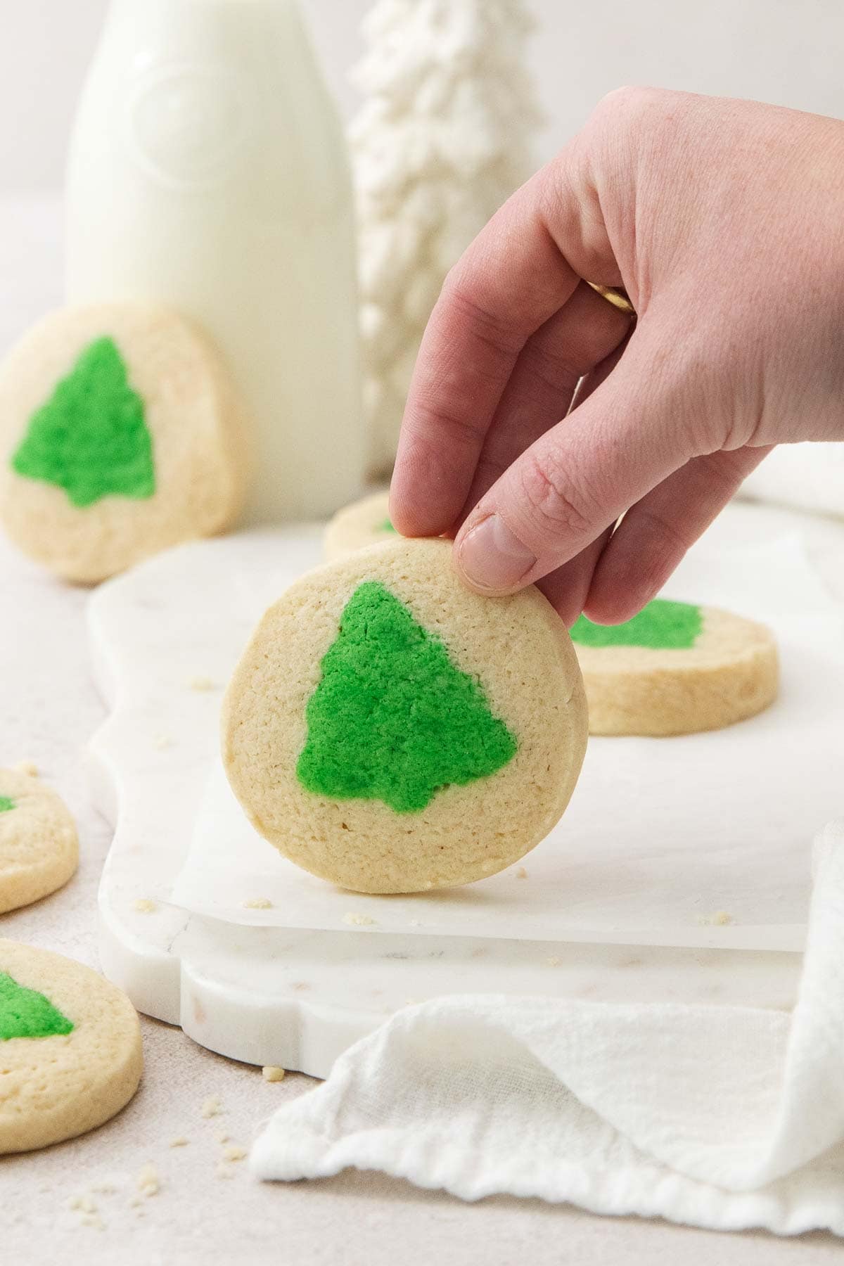 a hand holding up one slice and bake cookie with more in the background.