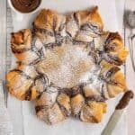 nutella star bread dusted with powdered sugar on a parchment covered wire rack.