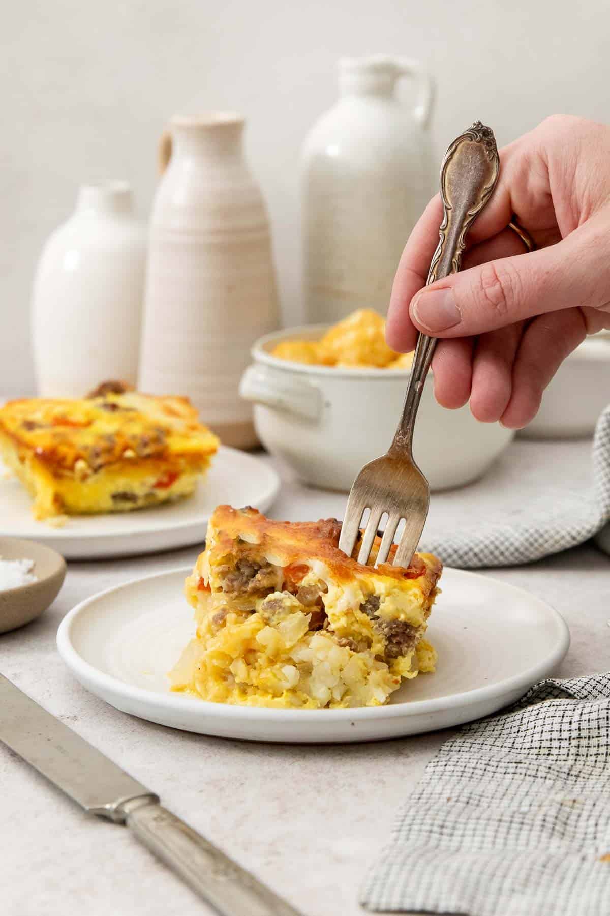 a fork being stuck into a slice of tater tot breakfast casserole.