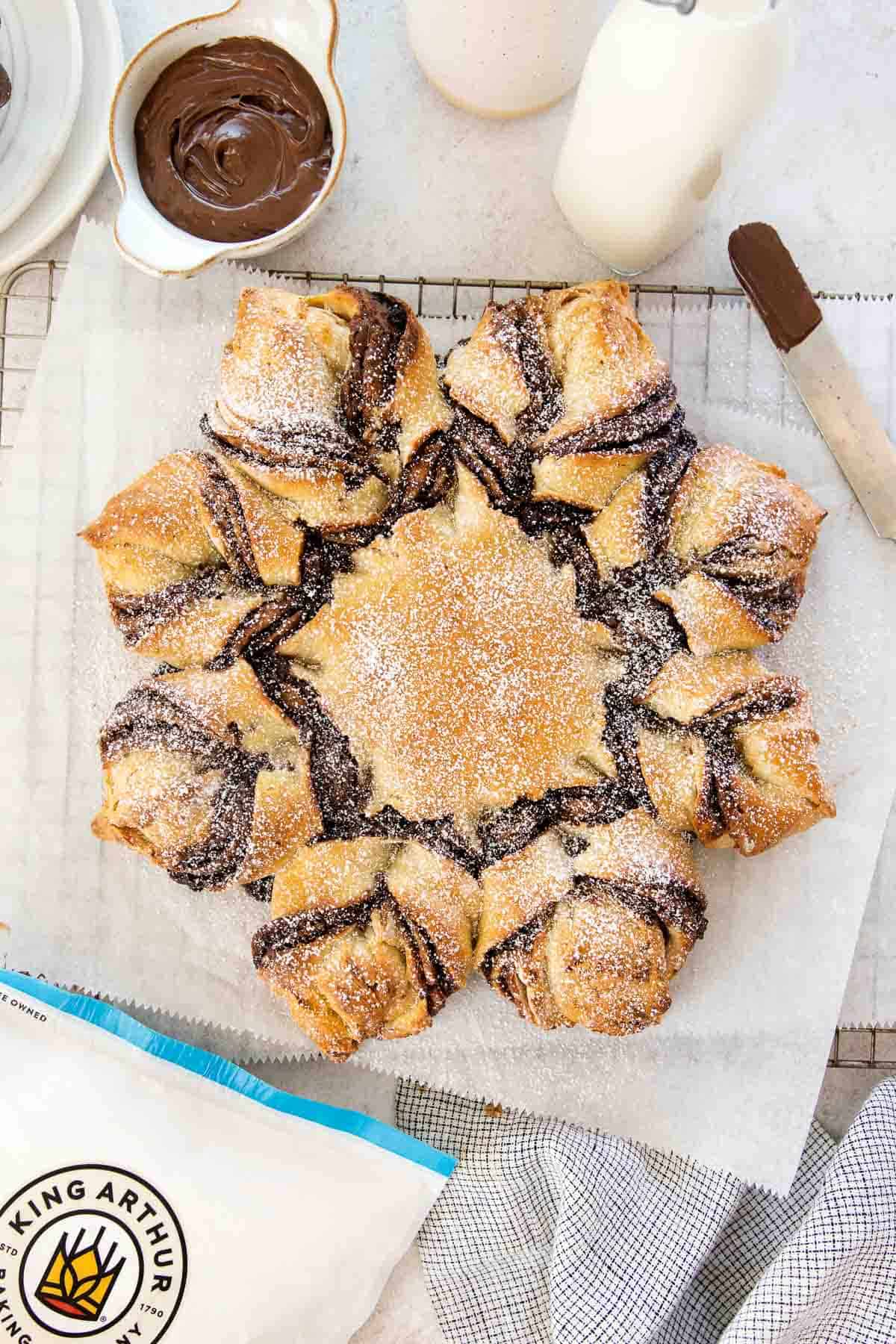 overhead view of nutella star bread with powdered sugar on a parchment-lined wire rack.