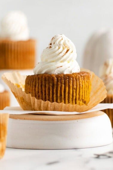 pumpkin pie cupcake with wrapper off topped with whipped cream
