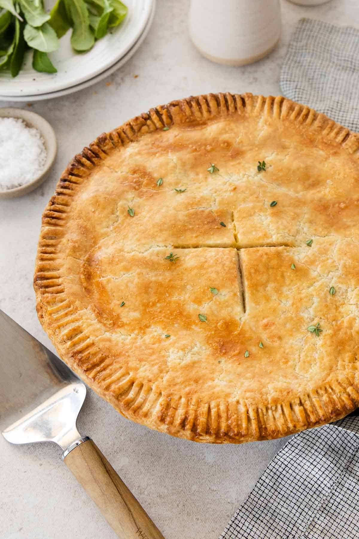 Gluten-free chicken pot pie on a table with a pie server and towel next to it.