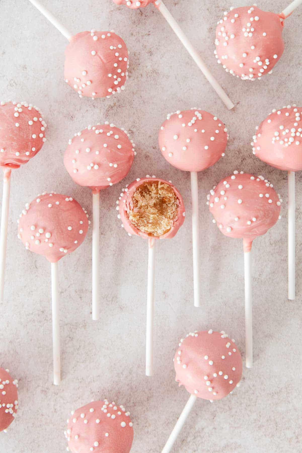 Gluten-free cake pops lined up on a countertop, with a bite taken out of one of them.
