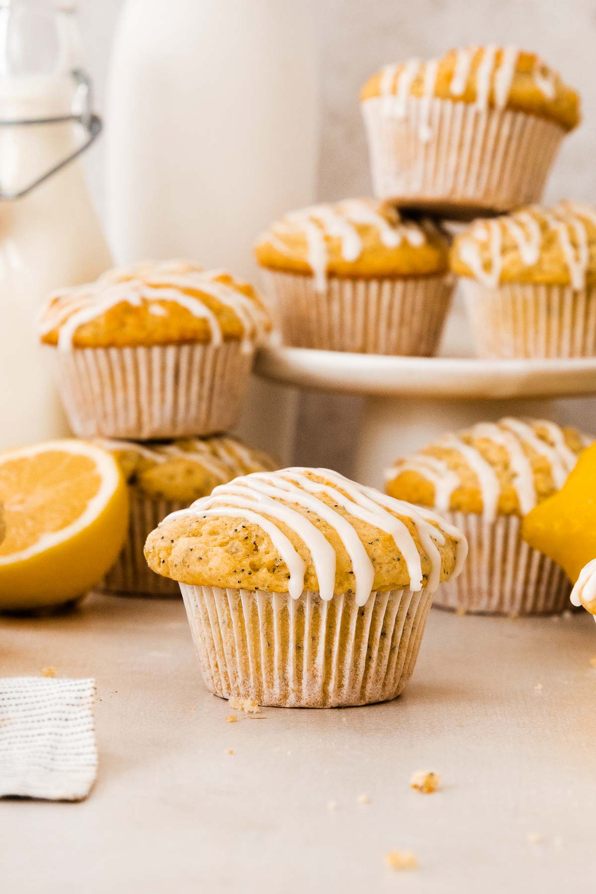 a glazed lemon poppy seed muffin in front of more muffins and lemons.