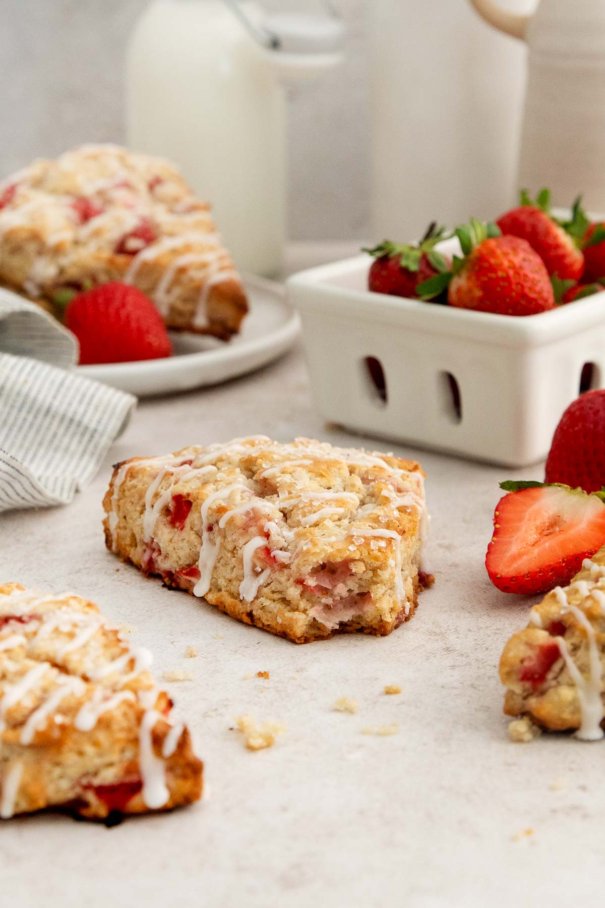 a strawberry scone with one bite missing and more scones and strawberries around.