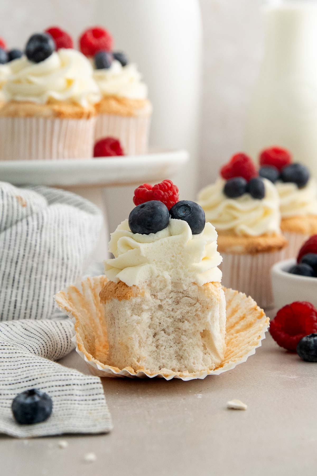 an angel food cake cupcake with one bite missing to show the inside crumb.