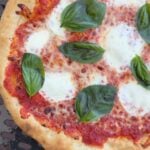 close up of artisan pizza with cheese and basil.