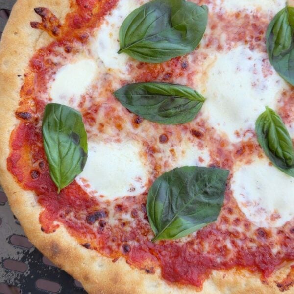 close up of artisan pizza with cheese and basil.