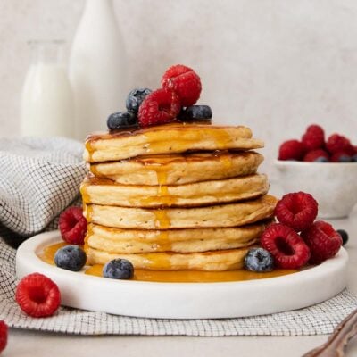 a stack of cottage cheese pancakes with berries and syrup.