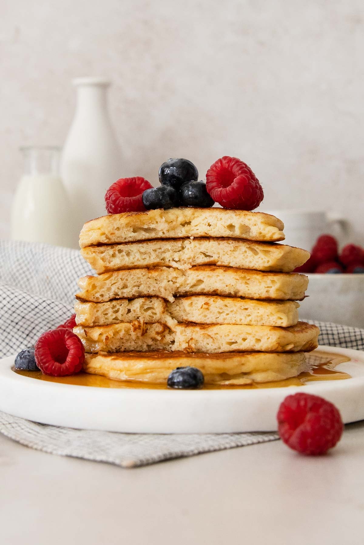 a stack of cottage cheese pancakes showing the inside and topped with berries and syrup.