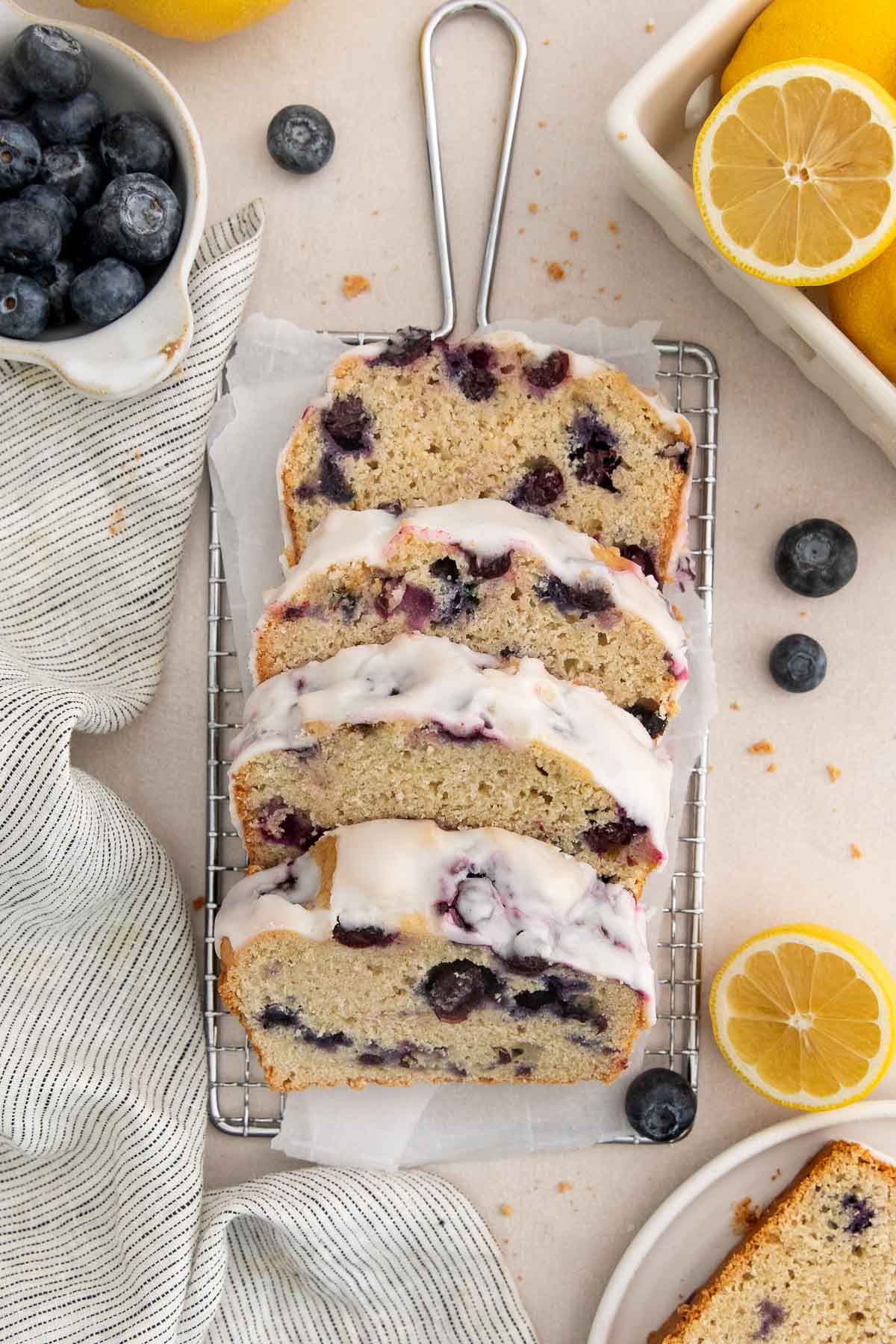 slices of glazed lemon blueberry bread on a parchment lined wire rack.