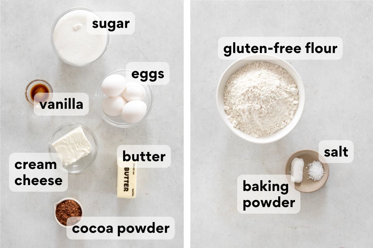 Labeled ingredients for baking: sugar, eggs, vanilla, cream cheese, cocoa powder, butter, gluten-free flour, salt, and baking powder, displayed in bowls and plates on a light surface.