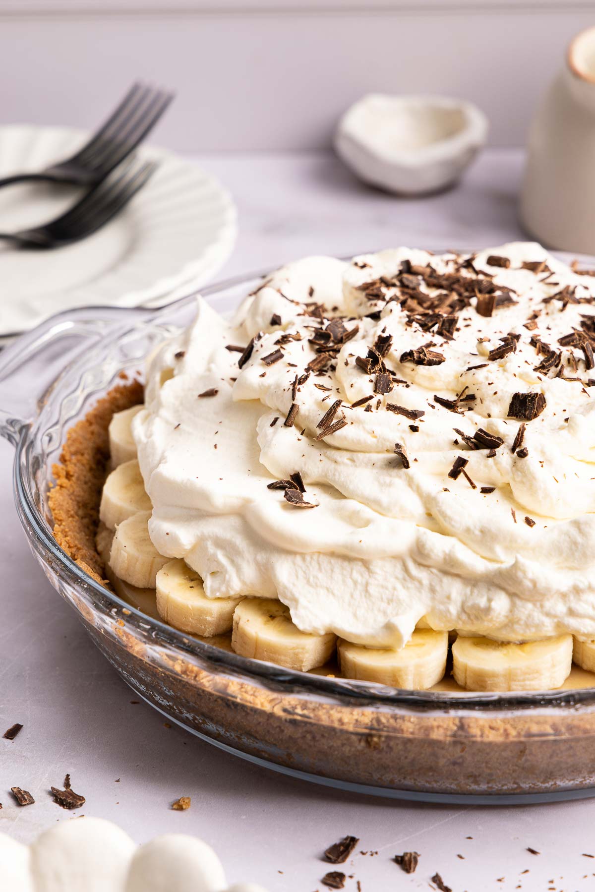 Banoffee pie in a glass dish topped with whipped cream and chocolate shavings.