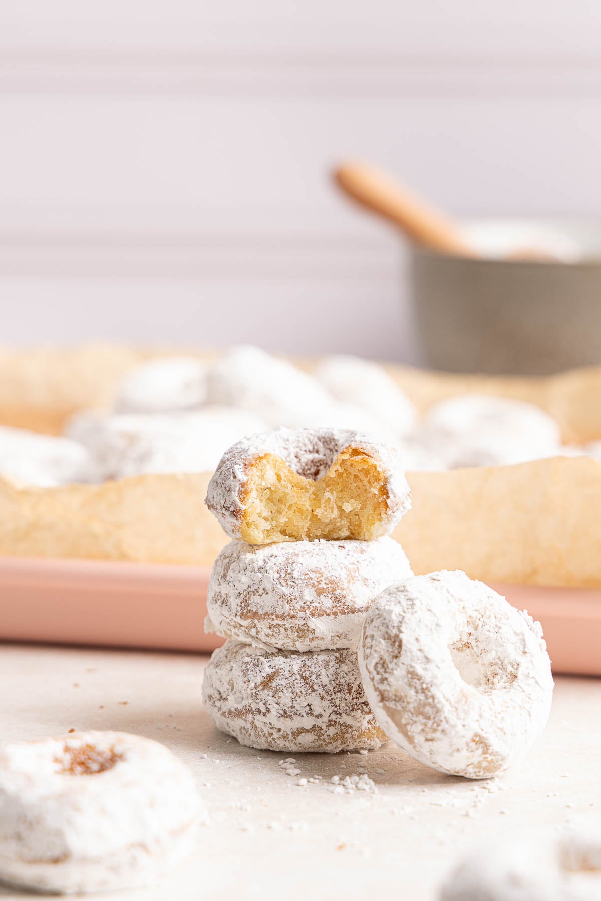 A stack of powdered sugar donuts, with the top donut bitten to show the interior.