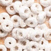 A pile of small, round donuts covered in powdered sugar.