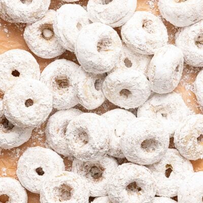 A pile of small, round donuts covered in powdered sugar.