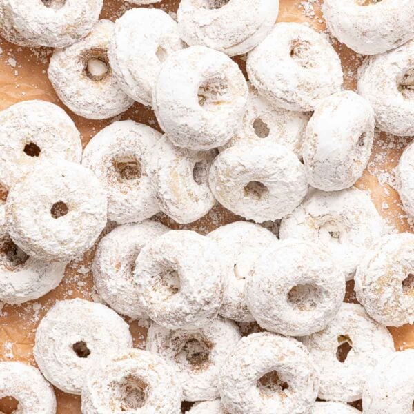 A pile of small, round donuts covered in powdered sugar.